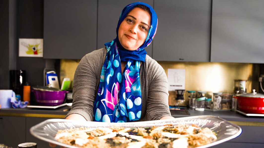 Female chef offering a plate of food to the camera